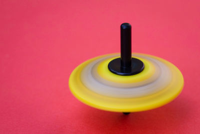 Close-up of spinning top over pink background