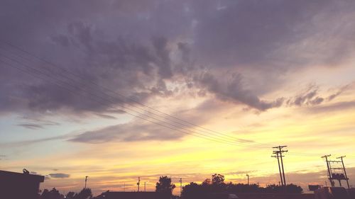 Low angle view of silhouette electricity pylon against sky during sunset