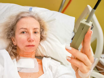 High angle view of young woman using mobile phone while lying on bed