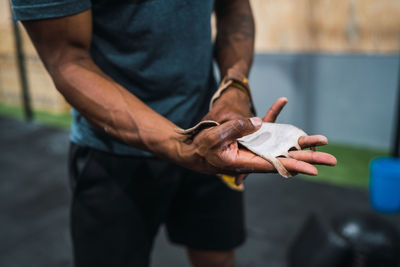 Midsection of man wearing sports glove in hand in gym