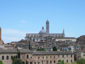 Buildings in city against clear blue sky