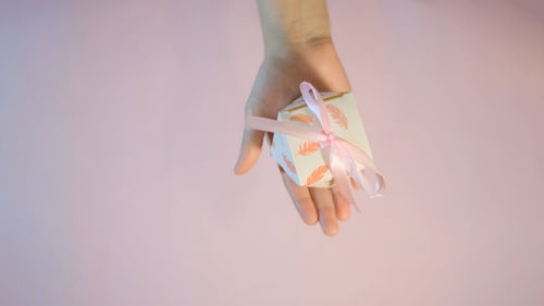 Close-up of hand holding paper over colored background