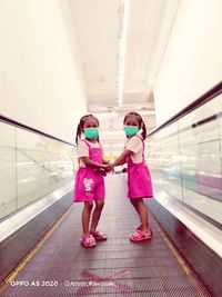 Rear view of women standing on escalator