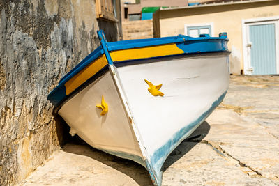 Close-up of yellow fising boat gainst wall