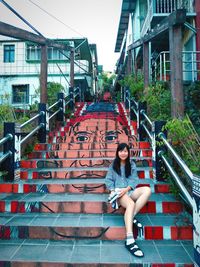 Portrait of smiling young woman sitting on steps with graffiti