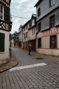 Man walking on street amidst buildings in city