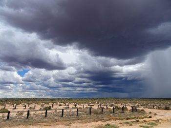 Scenic view of field against storm clouds