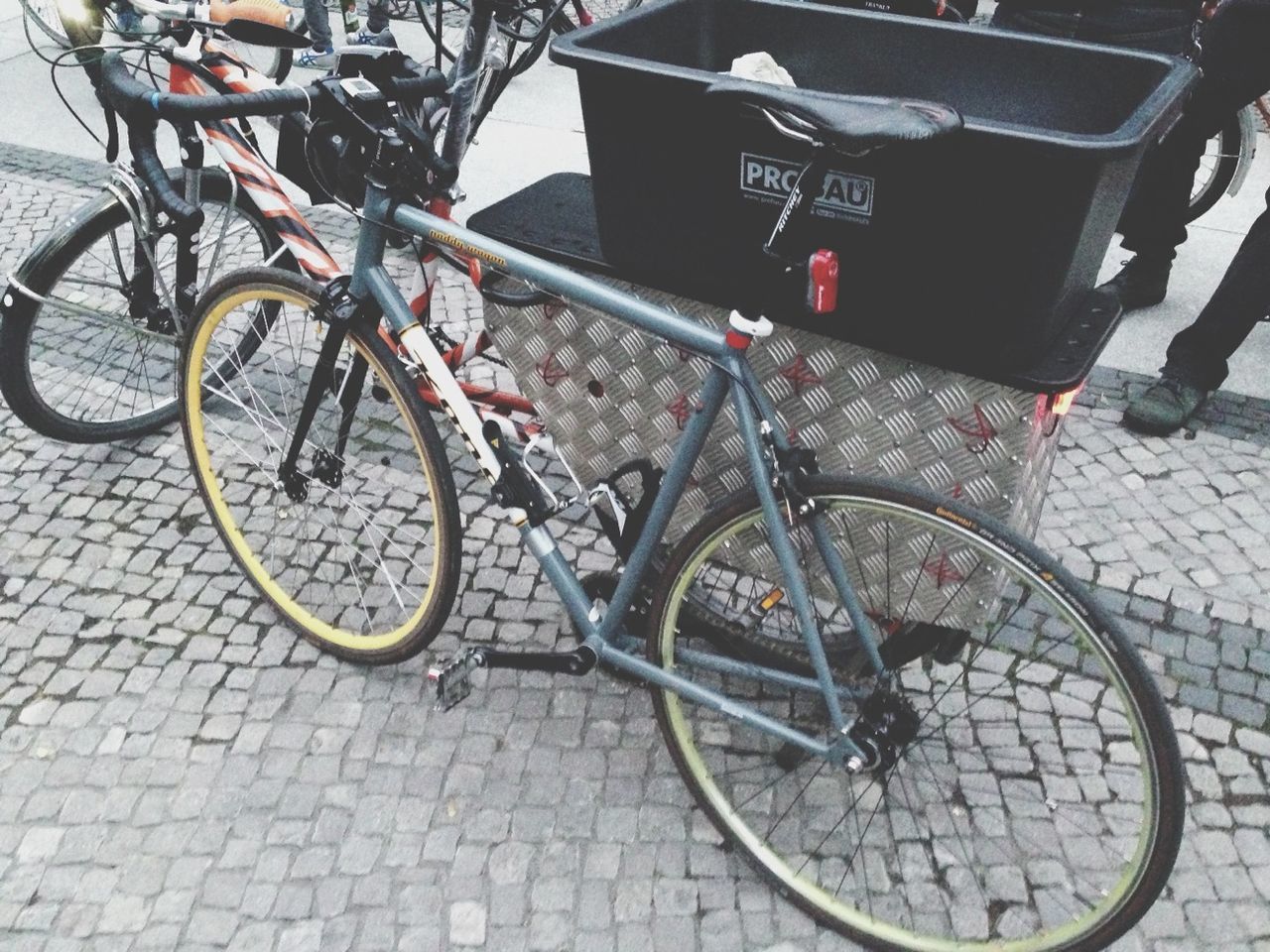 bicycle, transportation, mode of transport, land vehicle, stationary, parking, parked, street, cobblestone, sidewalk, travel, day, outdoors, paving stone, parking lot, wheel, footpath, sunlight, no people, car