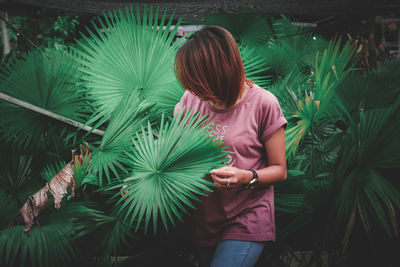 Rear view of young woman standing by tree