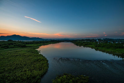 Scenic view of river against sky at sunset