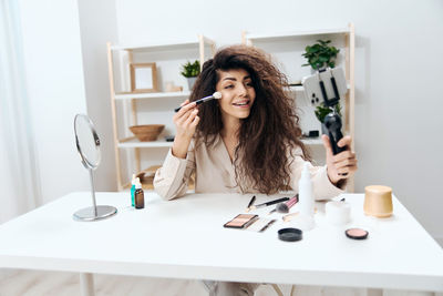 Portrait of young woman using mobile phone while sitting on table