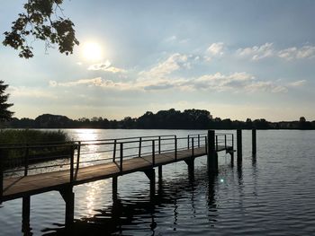 Pier over lake against sky during sunset