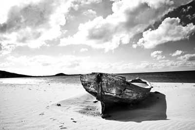 Abandoned boat on beach against sky