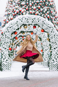 A young stylish woman is having fun and crewing. a festive christmas market in the background.