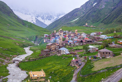 Scenic view of townscape by mountain against sky