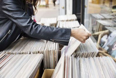 Midsection of woman selecting magazine at market stall