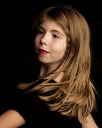 Close-up of young woman against black background