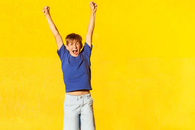 Portrait of smiling young man standing against yellow wall