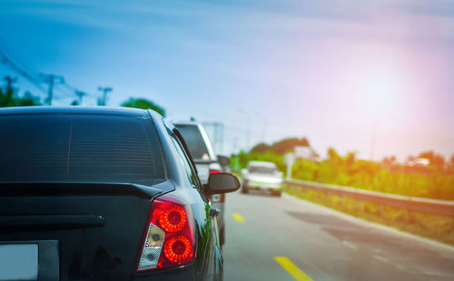 Vehicles on road against sky in city