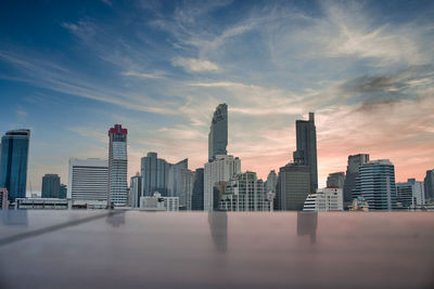 Modern buildings in city against sky during sunset