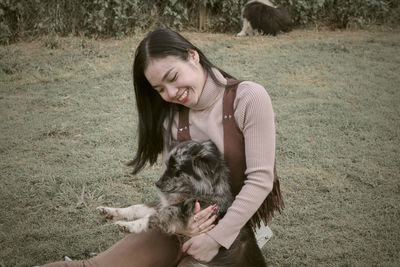 Side view of young woman with dog on field