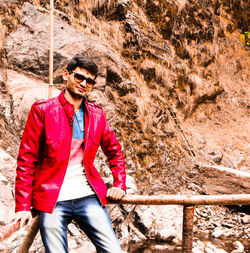 Young man wearing sunglasses standing on rock