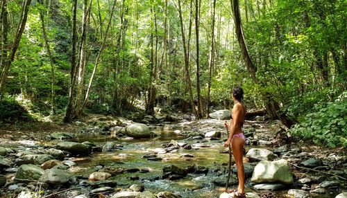 Rear view of woman climbing on rock in forest