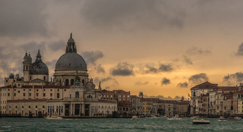 Grand canal amidst santa maria della salute and building against cloudy sky