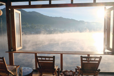 Chairs and table against sky seen through window