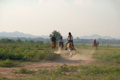 People riding motorcycle on field against sky