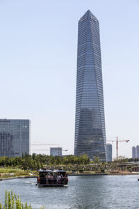 Boat moving on lake against northeast asia trade tower in city