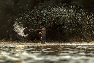 Full length of boy holding plants in lake