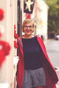 Smiling young woman standing against red wall