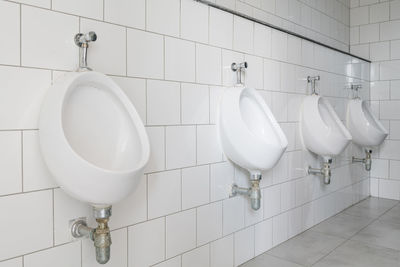 Urinals on tiled wall in public restroom