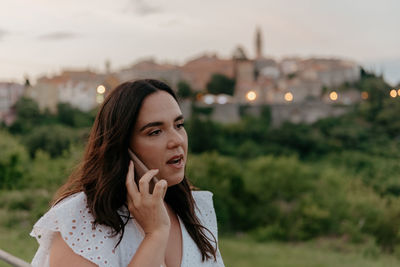 Candid portrait of young woman talking on the phone in city