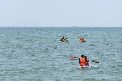 People in boat on sea against clear sky