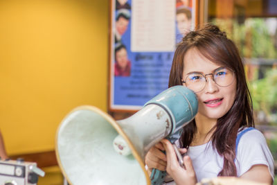 Portrait of smiling young woman holding megaphone