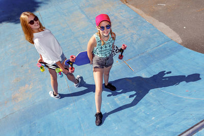 High angle portrait of friends with skateboards in city during sunny day