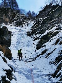 Rear view of man walking on snowcapped mountain