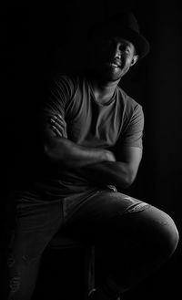 Young man sitting against black background