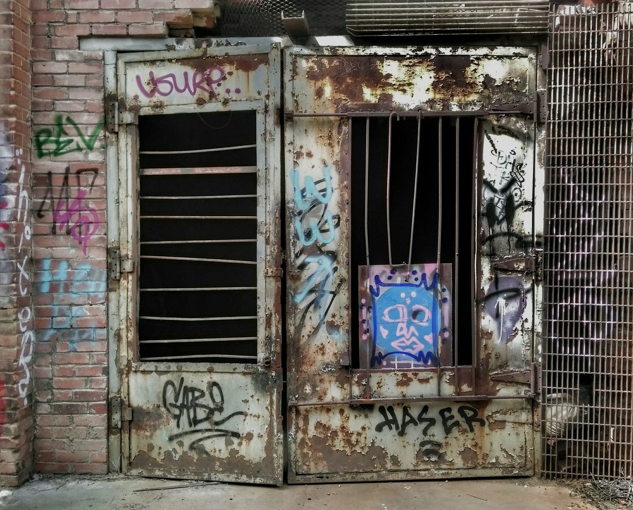 text, architecture, built structure, building exterior, door, western script, communication, window, closed, wall - building feature, old, graffiti, abandoned, house, damaged, wall, weathered, entrance, day, no people