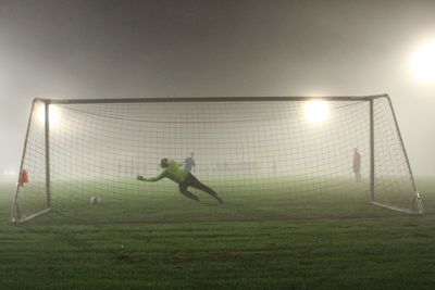 Penalty shot out - amateur football game on a foggy evening - goalie stretching