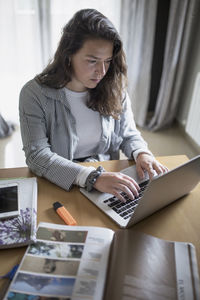 Woman using mobile phone while sitting on table