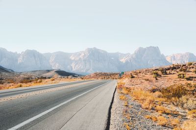 Road by mountains against clear sky