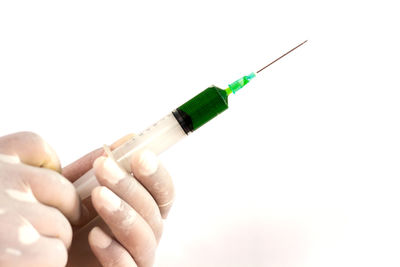 Close-up of hand holding cigarette over white background