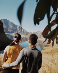 Rear view of couple looking at lake against mountains