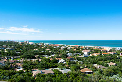 High angle view of buildings and sea against blue sky