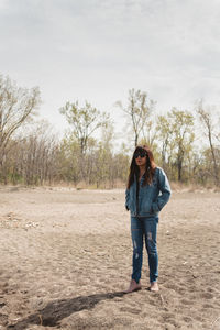 Full length portrait of young woman standing on field