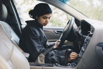 Female mechanic adjusting knob on dashboard in car