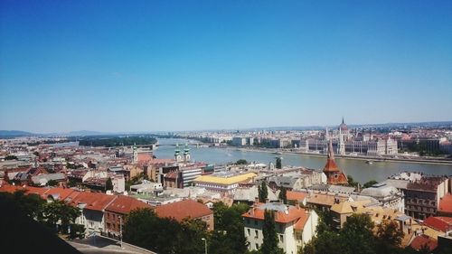 High angle view of river by buildings against clear blue sky